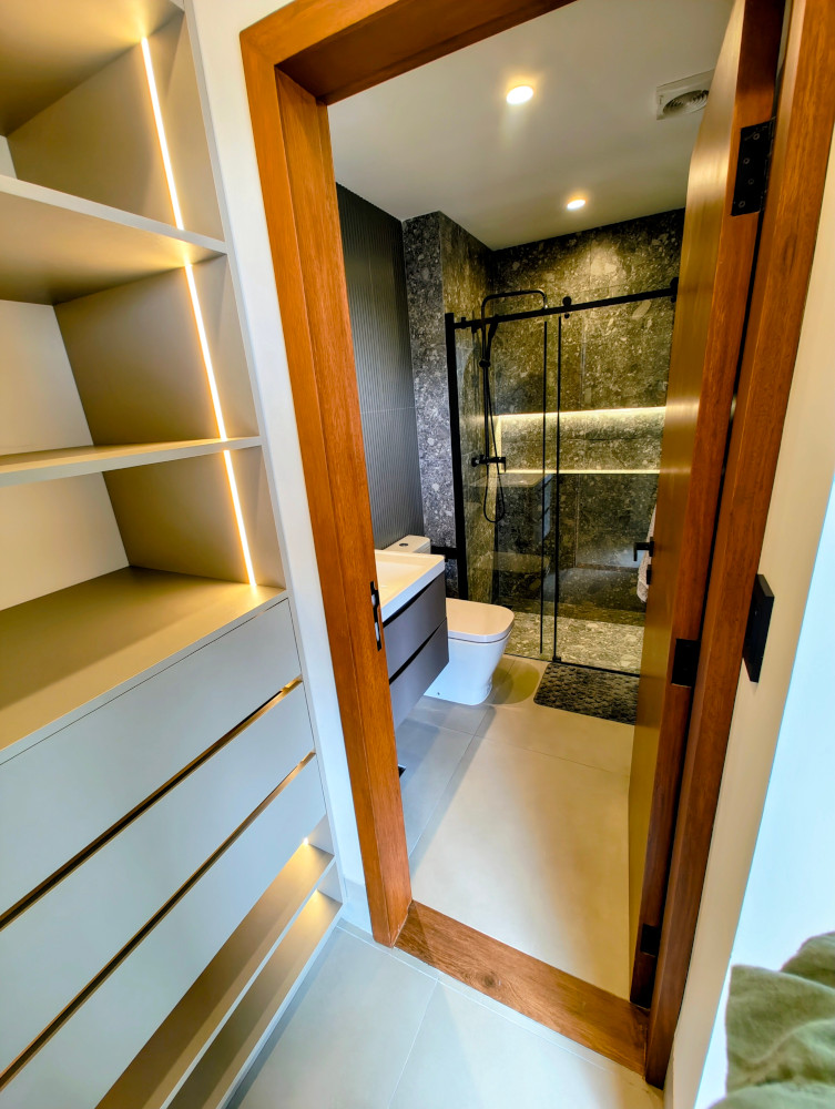 Bathroom with floating vanity, walk-in shower with glass door, and stone-look tile
