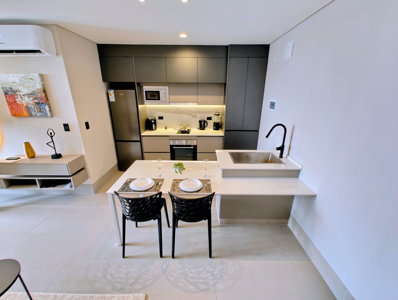 Modern kitchenette with integrated appliances and laundry behind a tall cabinet