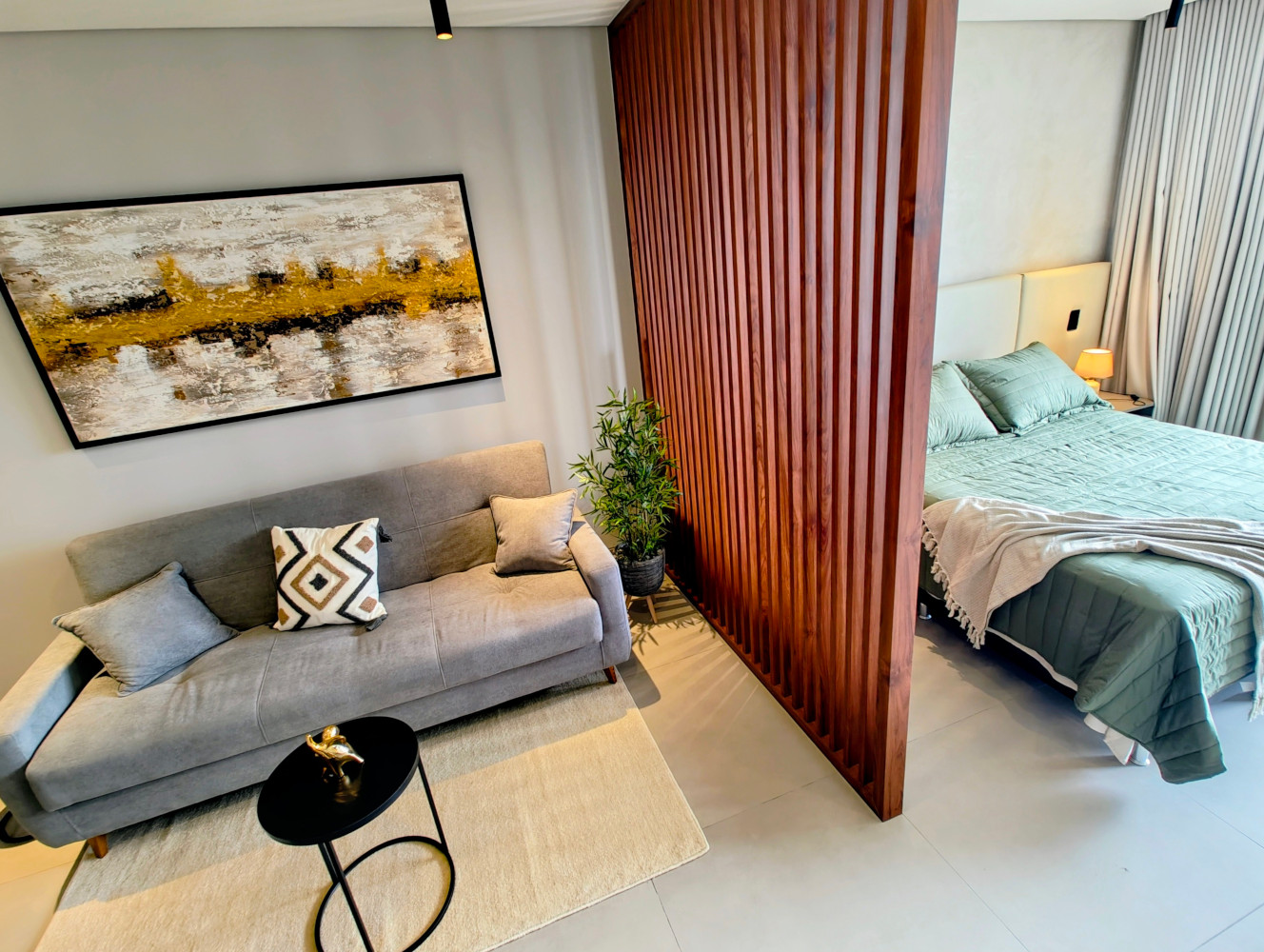 Living area with sofa and wooden slat partition separating the sleeping zone