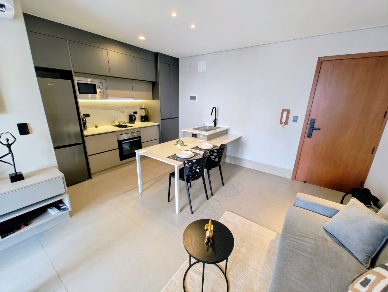 Open-plan kitchen, dining island, and living area in the furnished studio